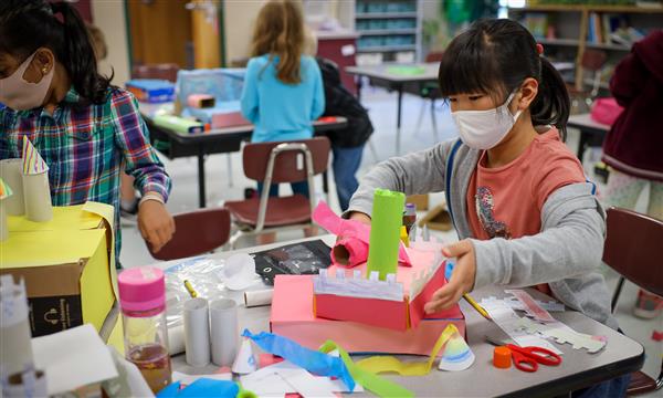 Student glues recycled materials together